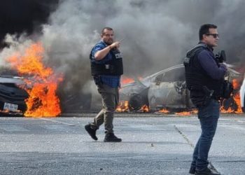 Petugas polisi mengamankan area tempat kendaraan dibakar oleh anggota geng di Zapopan, Meksiko, menyusul kematian ‘El Mencho’ © Gilberto Gall/Reuters