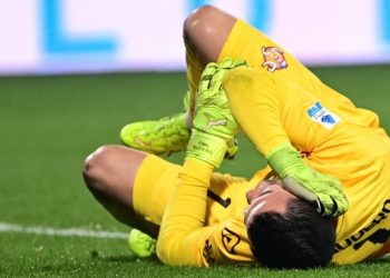 Kiper Cremonese asal Indonesia Emil Audero memegangi telinga usai terkena lemparan flare. (AFP/PIERO CRUCIATTI)